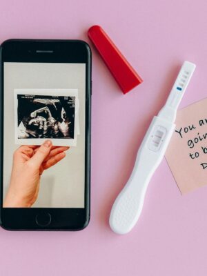 Pink background with a pregnancy test, ultrasound image, and a note for a dad-to-be.